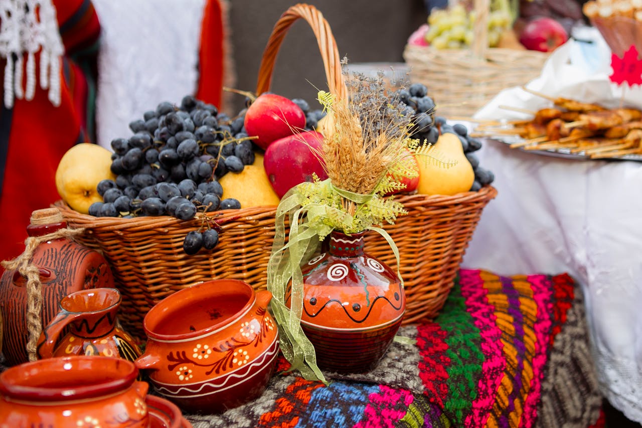 Colorful autumn harvest basket featuring fruits and traditional pottery captured at a market stall.