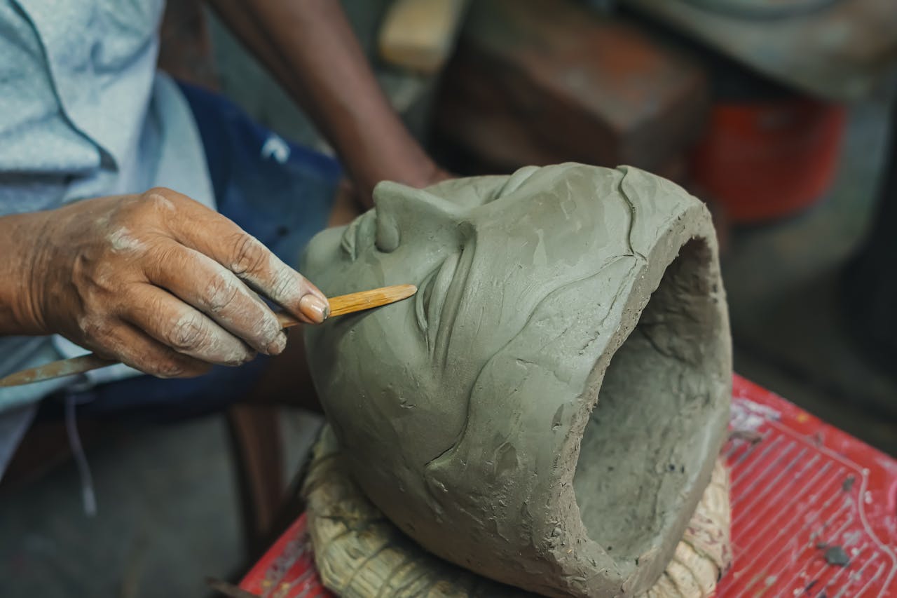Detailed view of an artisan handcrafting a clay sculpture in Kolkata, India.